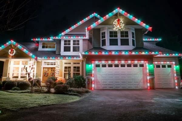 Red green and white C7 and C9 permanent lights installed along a home roofline